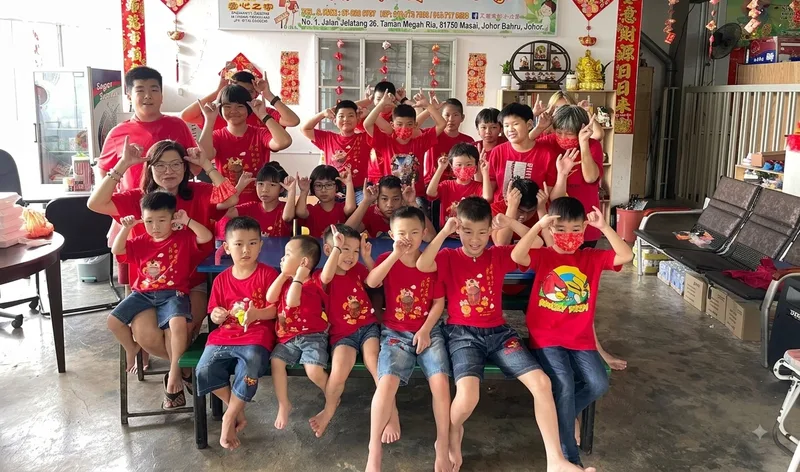 The whole shelter — around 30 children and two caregivers in red Lunar New Year shirts — posing together for a group photo