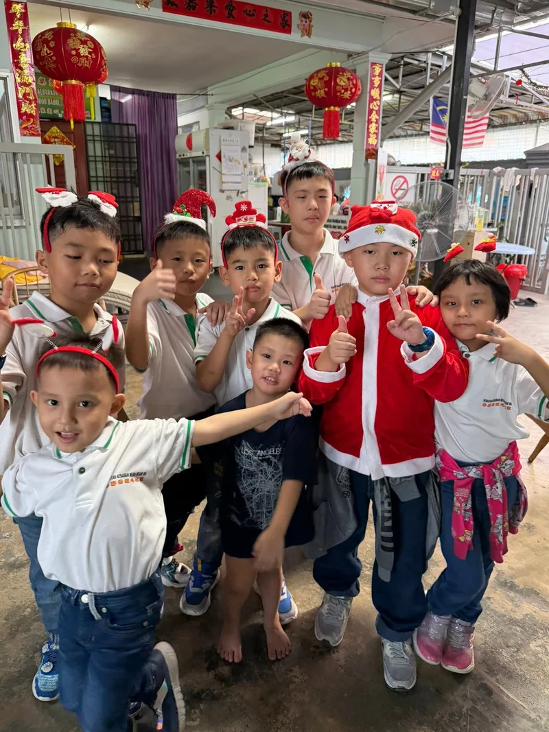 A large group of children posing together outside the shelter under its signboard